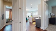 This thoughtfully designed single-floor residence offers a seamless open-concept layout that connects the kitchen, dining, and living areas into one cohesive, light-filled space. Rich hardwood flooring runs throughout the main living areas, anchoring the contemporary aesthetic.

The kitchen is a standout feature, showcasing a two-tone design with crisp white upper cabinetry and slate-gray lower cabinets, complemented by a bright white countertop island, subway tile backsplash, stainless steel appliances, and modern pendant lighting overhead. Recessed lighting and large windows ensure the space is generously illuminated.

The living room is warm and inviting, with multiple windows and a sliding glass door that opens onto a private balcony, offering pleasant views of mature trees. Natural light pours in through sheer curtains, enhancing the airy feel of the space.

The bedroom features plush carpet flooring, a bold navy accent wall, and bold graphic window treatments, lending the room a distinct, stylish character. The primary bathroom is generously proportioned, with dark slate tile floors, a dual-sink gray vanity with white countertops, a separate walk-in shower, and track lighting above a large mirror. A second full bathroom features a tub-shower combination, matching gray cabinetry, and coordinating tile finishes throughout.