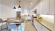 Located on Spruce Street in the heart of Philadelphia, this single-floor residence offers a thoughtfully designed layout with a bright, open feel throughout. Polished hardwood floors extend across the expansive living and bedroom areas, complemented by crisp white walls, crown molding, and recessed lighting that create a clean, classic aesthetic.

The kitchen is a standout feature, outfitted with white shaker-style cabinetry, dark countertops, a white subway tile backsplash, stainless steel appliances including a professional-grade gas range, and a central island with seating — all illuminated by stylish pendant lighting and recessed fixtures. Porcelain tile flooring grounds the space with a refined, practical finish.

The bedrooms are generously proportioned with hardwood floors, crown molding, and built-in closet organizers providing ample storage. The bathrooms are elegantly finished, featuring classic black-and-white mosaic tile flooring, a glass-enclosed shower, a soaking tub, and wainscoting details. A powder room with neutral tile offers additional convenience. The open-plan living and dining areas flow seamlessly, offering a welcoming and versatile space ideal for both everyday living and entertaining.