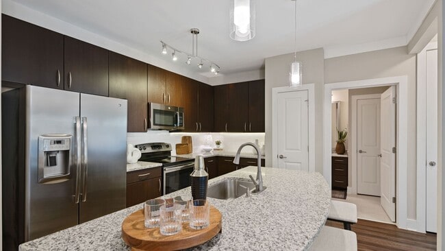Kitchens with granite counters, subway tile backsplash and side-by-side stainless steel refrigerator with exterior ice/water dispenser - Marshall Park Apartments + Townhomes
