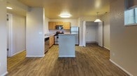 This single-floor residence offers a practical and comfortable layout designed for everyday living. The heart of the home is an open-concept kitchen, outfitted with warm honey-toned wood cabinetry, light countertops, and a full suite of stainless steel appliances including a refrigerator, electric range, built-in microwave, and dishwasher. A central kitchen island provides additional prep and dining space, while wood-look plank flooring ties the kitchen and living areas together seamlessly. A walk-in closet is conveniently accessible just off the kitchen area, adding valuable storage.

The bedrooms are generously sized, each featuring plush wall-to-wall carpeting and windows fitted with blinds that allow for natural light while maintaining privacy. The neutral wall tones throughout the space create a calm, versatile backdrop adaptable to a variety of furnishing styles.

The bathroom is thoughtfully appointed with a combination tub and shower, a wood-cabinet vanity topped with a speckled countertop, and wood-look flooring that complements the rest of the unit. A textured ceiling finish is consistent throughout the space, adding a subtle design element. Overall, this residence delivers a clean, functional, and welcoming environment suitable for comfortable day-to-day living.