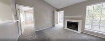 Located at 100 Hickory Highlands Dr in Antioch, TN, this 610-square-foot apartment offers 2 bedrooms and 1 bathroom across a single floor. The open-concept living room features vaulted ceilings, plush carpet flooring, neutral gray walls, and a white-mantled fireplace flanked by large windows that fill the space with natural light. The galley-style kitchen is equipped with white cabinetry, white countertops, wood-look vinyl flooring, and black or stainless steel appliances including a range and refrigerator, and flows seamlessly into the living area via a peninsula counter. The primary bedroom measures 150 square feet and showcases vaulted ceilings, carpet flooring, a natural light window, and a walk-in closet with a built-in rod. The secondary bedroom also features carpet flooring and a large window with outdoor views. The bathroom includes a full tub-shower combo with white tile surround, wood-look vinyl flooring, and white cabinetry. A dedicated closet provides additional storage. The unit's consistent neutral palette and vaulted ceilings create a clean, airy ambiance throughout.