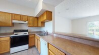 Located at 51 Great Trail Cir in Pickerington, Ohio, this two-story home offers a practical and well-organized layout across both levels. The kitchen is equipped with warm oak cabinetry, ample counter space, a stainless steel sink, an electric range, a dishwasher, and a full-size refrigerator, all set on easy-care tile flooring. A pass-through counter connects the kitchen to the main living area, creating an open, communicative flow between the two spaces. The living area is generously sized, finished with plush carpeting and neutral walls, and benefits from a staircase that leads to the upper level. A full bathroom on the main level features a tub/shower combination, a wood-vanity with a white countertop, and tile flooring. Upstairs, the bedrooms are carpeted and bright, each with large windows that invite natural light and offer views of the surrounding greenery. The upper-level bathroom includes a walk-in shower with sliding glass doors and a matching oak vanity. Throughout the home, textured ceilings, wood-tone trim, and a consistent neutral color palette provide a cohesive and understated aesthetic. The layout is straightforward and functional, making effective use of space on both floors.