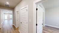 This single-story home in Madison, Alabama offers a well-designed layout across three bedrooms and two bathrooms. The open-concept kitchen and living area serves as the heart of the home, featuring light hardwood-style flooring, neutral wall tones, and a ceiling fan with integrated lighting. The kitchen is equipped with white shaker-style cabinetry, stainless steel appliances, a central island with a white countertop and undermount sink, and pendant lighting overhead, creating a clean, modern aesthetic.

The hallway connects the bedrooms with white panel doors accented by matte black hardware, maintaining a cohesive design throughout. The primary bedroom includes a walk-in closet outfitted with wire shelving on both sides. The bathrooms feature white vanities with framed mirrors and matte black fixtures; one bathroom includes a tub-shower combination with built-in shelving.

A dedicated laundry room accommodates a full-size washer and dryer with overhead wire shelving. The attached garage provides additional utility space with a garage door opener installed. Throughout the home, light hardwood-style flooring and neutral finishes contribute to a bright, clean, and cohesive atmosphere.