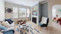 This thoughtfully designed 2-bedroom, 2-bathroom residence at The Heritage offers a comfortable and functional single-floor layout with refined finishes throughout. The living room serves as the heart of the home, featuring a classic fireplace with a white surround, a built-in display niche above, crown molding, soft carpet flooring, and large windows that fill the space with natural light and views of surrounding greenery. Adjacent to the living area, a dedicated dining space provides an inviting setting beneath a contemporary chandelier, with a bright window framing outdoor views. The kitchen is well-equipped with dark wood cabinetry, stainless steel appliances, a light marble-toned breakfast bar peninsula, and hardwood-style flooring, seamlessly connecting to the main living areas. Both bedrooms are generously sized, carpeted, and naturally lit through sizable windows. The primary suite includes a spacious walk-in closet with built-in wire shelving and an en-suite bathroom featuring a dual-sink vanity with warm wood cabinetry and hardwood-style tile flooring. A dedicated laundry room with full-size side-by-side washer and dryer units and overhead shelving adds everyday convenience. Crown molding and neutral tones unify the home's cohesive, welcoming aesthetic.