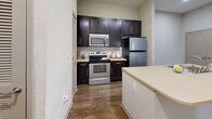 Located at 11920 Joleen Ct in Huntersville, NC, this two-bedroom, one-bathroom residence offers a well-designed single-floor layout with a comfortable and functional living environment. The open-concept living and kitchen area is anchored by rich hardwood-style flooring throughout, creating a cohesive and inviting atmosphere. The kitchen is well-appointed with dark espresso cabinetry, stainless steel appliances including a refrigerator, range, and microwave, a subway tile backsplash, light countertops, and a central island with a built-in sink — ideal for both cooking and casual dining. The living room features crown molding, a ceiling fan, and access to an exterior door, allowing for natural light to filter in. Both bedrooms are finished with plush carpet and ceiling fans, offering a cozy retreat. The primary bedroom includes access to a dedicated closet with built-in shelving. The bathroom features a dark-cabinet vanity with a large mirror, light countertop, and hardwood-style flooring. Additional closet storage is available throughout the home. Neutral wall tones and recessed lighting contribute to a clean, modern aesthetic throughout this well-maintained Huntersville residence.