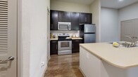 Located at 11920 Joleen Ct in Huntersville, NC, this two-bedroom, one-bathroom residence offers a well-designed single-floor layout with a comfortable and functional living environment. The open-concept living and kitchen area is anchored by rich hardwood-style flooring throughout, creating a cohesive and inviting atmosphere. The kitchen is well-appointed with dark espresso cabinetry, stainless steel appliances including a refrigerator, range, and microwave, a subway tile backsplash, light countertops, and a central island with a built-in sink — ideal for both cooking and casual dining. The living room features crown molding, a ceiling fan, and access to an exterior door, allowing for natural light to filter in. Both bedrooms are finished with plush carpet and ceiling fans, offering a cozy retreat. The primary bedroom includes access to a dedicated closet with built-in shelving. The bathroom features a dark-cabinet vanity with a large mirror, light countertop, and hardwood-style flooring. Additional closet storage is available throughout the home. Neutral wall tones and recessed lighting contribute to a clean, modern aesthetic throughout this well-maintained Huntersville residence.