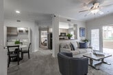 This thoughtfully designed single-floor residence offers a seamless open-concept layout that connects the living, dining, and kitchen areas into one cohesive living space. The living room is bright and welcoming, featuring plush carpeting, crown molding, a ceiling fan, and sliding glass doors that open to a private balcony, allowing natural light to fill the interior. Recessed lighting and decorative columns add architectural character throughout.

The galley-style kitchen is efficiently laid out with light wood cabinetry, dark granite-style countertops, tile flooring, and a full suite of stainless steel appliances including a refrigerator with ice maker, electric range, built-in microwave, and dishwasher. A window above the countertop brings in additional natural light.

The dining area is conveniently positioned adjacent to the kitchen and features carpet flooring and crown molding. A dedicated in-unit laundry closet with a full-size washer and dryer is accessible directly from this space.

Both bedrooms are carpeted and well-sized, each outfitted with a ceiling fan and large windows dressed with vertical blinds and sheer curtains. The full bathroom includes tile flooring, a single-sink vanity with light wood cabinetry, and a shower-tub combination.