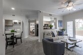 This thoughtfully designed single-floor residence offers a seamless open-concept layout that connects the living, dining, and kitchen areas into one cohesive living space. The living room is bright and welcoming, featuring plush carpeting, crown molding, a ceiling fan, and sliding glass doors that open to a private balcony, allowing natural light to fill the interior. Recessed lighting and decorative columns add architectural character throughout.

The galley-style kitchen is efficiently laid out with light wood cabinetry, dark granite-style countertops, tile flooring, and a full suite of stainless steel appliances including a refrigerator with ice maker, electric range, built-in microwave, and dishwasher. A window above the countertop brings in additional natural light.

The dining area is conveniently positioned adjacent to the kitchen and features carpet flooring and crown molding. A dedicated in-unit laundry closet with a full-size washer and dryer is accessible directly from this space.

Both bedrooms are carpeted and well-sized, each outfitted with a ceiling fan and large windows dressed with vertical blinds and sheer curtains. The full bathroom includes tile flooring, a single-sink vanity with light wood cabinetry, and a shower-tub combination.