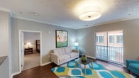 This single-floor residence offers a thoughtfully designed open-concept layout connecting the living, dining, and kitchen areas. The living room features dark hardwood flooring, crown molding, a textured ceiling, and a sliding glass door leading to a private balcony with outdoor views. The kitchen is equipped with dark granite countertops, rich wood cabinetry, stainless steel appliances including a French door refrigerator and microwave, and a breakfast bar illuminated by pendant lighting. The adjacent dining area provides a seamless flow between spaces.

The primary bedroom includes carpet flooring, a large window with exterior views, a decorative ceiling fixture, and ample space for furnishings. The en-suite bathroom features dual sinks with granite countertops, a glass-enclosed shower, and tile flooring. The second bedroom is comfortably sized with carpet flooring, a double-door closet, and coordinating finishes throughout. A second full bathroom with a tub-shower combination and tile flooring serves this bedroom. Neutral gray tones and consistent finishes create a cohesive aesthetic throughout the entire residence.