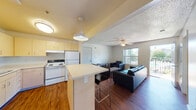 Located at 90 Common Dr in Eugene, Oregon, this single-floor unit offers a practical and well-organized layout. The open-concept design seamlessly connects the kitchen and living area, creating a cohesive and functional space. The kitchen is equipped with light wood cabinetry, a full suite of white appliances including a refrigerator, electric range, dishwasher, and microwave, along with generous counter space and a peninsula with bar seating — ideal for casual dining or meal prep. The adjoining living area features warm wood-style flooring, a ceiling fan with light fixture, and large windows that allow abundant natural light and provide views of the outdoor surroundings, including what appears to be a shared outdoor area. A balcony door off the living room adds further access to the outdoors. The bathroom is clean and functional, featuring a white vanity with storage drawers and cabinet, a large mirror with overhead lighting, and wood-style flooring. The bedroom offers carpeted flooring, a ceiling fan, and a textured ceiling, providing a comfortable and quiet retreat. Throughout the unit, the neutral color palette and consistent finishes contribute to a cohesive, move-in ready atmosphere suited for everyday living.