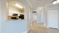 Located at 14330 58th St N in Largo, Florida, this single-floor residence offers a thoughtfully designed open layout with a seamless flow between living spaces. The living area is highlighted by crown molding, a ceiling fan, and light-toned wood-style flooring that extends throughout much of the unit. A sliding glass door at the end of the living room frames serene water views, filling the space with natural light and a relaxing Florida ambiance.

The kitchen is well-appointed with white shaker-style cabinetry, granite countertops, a decorative tile backsplash, and black appliances including a range, dishwasher, microwave, and refrigerator. An arched pass-through connects the kitchen to the living area, adding an architectural touch that enhances the open feel.

A hallway lined with elegant arched doorways leads to the bedrooms and bathrooms. The bathrooms feature granite-topped vanities, wood-style flooring, and tiled tub-shower combinations. The primary bedroom includes a spacious walk-in closet with wire shelving for ample storage. A dedicated laundry area with an in-unit washer provides added convenience. Crown molding and neutral tones are consistent throughout, contributing to a clean, cohesive aesthetic.