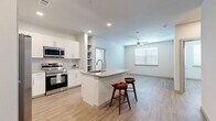 This thoughtfully designed 2-bedroom, 2-bathroom residence offers a clean, modern aesthetic with light wood-style flooring and a neutral color palette carried consistently throughout the single-floor layout. The open-concept kitchen and living area serves as the heart of the home, anchored by a central island with a granite countertop, undermount sink, and bar seating for two. The kitchen is well-appointed with white shaker cabinetry, granite countertops, a full suite of stainless steel appliances including a side-by-side refrigerator with ice maker, range, microwave, and dishwasher, and a tasteful tile backsplash. A built-in shelving nook adds additional storage and display space. The living area flows naturally from the kitchen and is illuminated by a ceiling fan and a bright window fitted with blinds. Both bedrooms are comfortably sized, each featuring a ceiling fan, a large window that invites natural light, and access to a closet. The primary bedroom is particularly spacious and includes a walk-in closet with wire shelving. The primary bathroom features a granite double-sink vanity with white cabinetry, a soaking tub, and striking marble-style tile surround. Two dedicated closets add to the overall storage capacity of this well-organized residence.