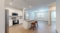 This thoughtfully designed 2-bedroom, 2-bathroom residence offers a clean, modern aesthetic with light wood-style flooring and a neutral color palette carried consistently throughout the single-floor layout. The open-concept kitchen and living area serves as the heart of the home, anchored by a central island with a granite countertop, undermount sink, and bar seating for two. The kitchen is well-appointed with white shaker cabinetry, granite countertops, a full suite of stainless steel appliances including a side-by-side refrigerator with ice maker, range, microwave, and dishwasher, and a tasteful tile backsplash. A built-in shelving nook adds additional storage and display space. The living area flows naturally from the kitchen and is illuminated by a ceiling fan and a bright window fitted with blinds. Both bedrooms are comfortably sized, each featuring a ceiling fan, a large window that invites natural light, and access to a closet. The primary bedroom is particularly spacious and includes a walk-in closet with wire shelving. The primary bathroom features a granite double-sink vanity with white cabinetry, a soaking tub, and striking marble-style tile surround. Two dedicated closets add to the overall storage capacity of this well-organized residence.