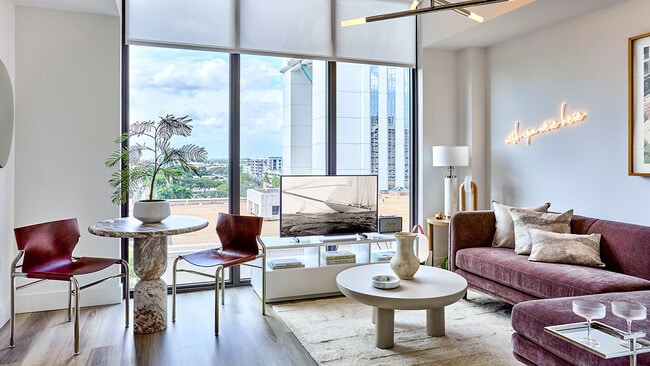 Sala de estar de un apartamento con ventanas de piso a techo y pisos estilo madera - Griffis West Palm