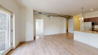 Located at 601 Lake Michigan Dr in Grand Rapids, Michigan, this 2-bedroom, 1-bathroom unit offers a thoughtfully designed open-concept layout that blends modern industrial aesthetics with everyday comfort. The combined kitchen and living area forms the heart of the unit, characterized by light-toned hardwood-style flooring, crisp white walls, and distinctive exposed metal ductwork that lends an urban, loft-inspired character to the space. Large windows and a glass-panel door flood the living area with natural light and provide direct access to a private balcony overlooking lush greenery.

The kitchen is well-appointed with rich dark-toned cabinetry, stainless steel appliances including a range, microwave, and refrigerator, and a generous granite-topped island with an undermount sink — ideal for both cooking and casual dining. Pendant lighting above the island adds a refined finishing touch.

Both bedrooms feature plush carpeting, ample closet space with sliding doors, and windows that invite natural light. The primary bedroom is a comfortable, well-proportioned retreat. The full bathroom is finished with large-format tile flooring, a dual-sink vanity with granite countertops, light wood cabinetry, and well-lit mirrors. A utility room rounds out the functional layout of this well-designed urban residence.