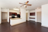 This single-floor residence in Midland, Texas offers a well-designed open-concept layout that seamlessly connects the kitchen, dining, and living areas. The kitchen is a standout feature, showcasing rich dark cherry cabinetry, granite countertops, and black appliances including a range, microwave, dishwasher, and refrigerator. A central island with a built-in sink and pendant lighting adds both functionality and style, while the galley-style layout maximizes workspace efficiency. Dark hardwood-style flooring runs throughout the main living areas, complementing the warm tones of the cabinetry and creating a cohesive aesthetic. The living area is generously proportioned, brightened by multiple windows that allow natural light to fill the space, and equipped with a ceiling fan for added comfort. The bedroom features plush carpeting, a ceiling fan, and direct access to a walk-in closet with built-in shelving. The bathroom is finished with matching granite countertops, dark cabinetry, a large vanity mirror, and a full tub-shower combination with white tile surround. Throughout the residence, consistent finishes and neutral wall tones create a clean, inviting atmosphere well-suited for everyday living in Midland, TX.