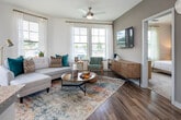This single-floor residence at 281 Lakeshore Pkwy in Homewood, Alabama, offers a thoughtfully designed open-concept layout with contemporary finishes throughout. Hardwood-style flooring flows across the main living areas, connecting the kitchen, dining, and living spaces seamlessly.

The kitchen is a functional centerpiece, featuring white shaker cabinetry, granite countertops, a subway tile backsplash, stainless steel appliances, and a peninsula island with bar seating and pendant lighting overhead. Built-in open shelving provides additional storage and display space.

The living area is bright and inviting, with multiple windows dressed in sheer curtains and blinds that allow natural light to fill the room. A ceiling fan adds comfort, and the space accommodates a comfortable seating arrangement.

The bedrooms are carpeted for warmth, with large windows offering natural light. The primary bedroom includes a bold accent wall and access to a well-sized bathroom featuring granite vanity countertops, gray cabinetry, hardwood-style flooring, a tub-shower combination, and an adjacent walk-in closet. A second bathroom with similar finishes serves additional occupants.

A corridor with a built-in desk workspace adds practical utility to the unit's overall design.