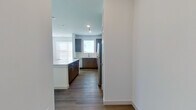 This well-appointed single-floor residence offers a thoughtfully designed layout encompassing one bedroom, one bathroom, a combined kitchen and living area, and a dedicated closet. The open-concept kitchen and living room serve as the heart of the home, featuring rich dark wood cabinetry, a large central island with a crisp white countertop, and a full suite of stainless steel appliances including a refrigerator, range, microwave, and dishwasher. Multiple windows fitted with horizontal blinds flood the space with natural light, while wood-look flooring runs seamlessly throughout, lending warmth and continuity to the interior. The bedroom is generously proportioned, benefiting from multiple windows that invite ample daylight and provide a bright, airy atmosphere, complemented by a ceiling fan for added comfort. The bathroom is elegantly finished with a wide dark wood vanity, white countertop, and a striking LED-backlit mirror that adds a modern, sophisticated touch alongside tall cabinetry for additional storage. Clean white walls, recessed lighting, and consistent flooring tie each room together in a cohesive, contemporary aesthetic that is both functional and visually refined.