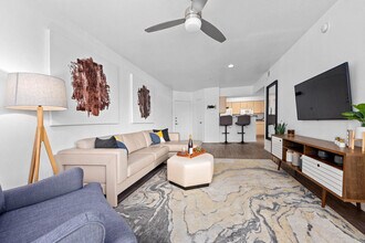 Living room with beige sectional, ceiling fan and wall-mounted TV on hardwood floors - Monterra