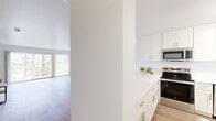 Located at 210 Lower Via Casitas in the charming Marin County city of Larkspur, California, this thoughtfully updated 1-bedroom, 1-bathroom residence offers a clean, modern aesthetic across a single floor. Light wood-tone flooring runs continuously throughout, lending warmth and visual cohesion to every room.

The renovated kitchen is a standout feature, showcasing white shaker cabinetry with brushed nickel hardware, gleaming marble-look quartz countertops, a stainless steel sink, dishwasher, refrigerator, and range with microwave above. A window above the sink invites natural light and garden views. The kitchen opens via a peninsula counter directly into the living area, creating a seamless and functional layout.

The spacious living room benefits from a ceiling fan, baseboard heating, and large windows with vertical blinds that frame lush greenery outside. The generously sized primary bedroom offers a tranquil retreat with a wide window overlooking mature trees, baseboard heating, and easy access to a dedicated closet.

The bathroom is clean and functional, featuring a full tub-shower combination with white tile surround and chrome fixtures. A separate vanity area with a white cabinet, large mirror, and built-in lighting provides added convenience. The bright, neutral palette throughout creates a calm and welcoming ambiance.