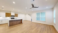 Located at 2654 Aruba Bend Dr in Katy, TX, this modern two-story home offers six bedrooms and five bathrooms across two well-proportioned floors. The main level provides the larger share of living space and is anchored by an open-concept kitchen and living area. The kitchen is a standout, featuring a striking quartz waterfall island, two-tone cabinetry with white lower cabinets and warm wood upper cabinets, a gas range, stainless steel appliances, and recessed lighting throughout. Light wood-look flooring flows seamlessly through the main living areas, complementing the bright white walls and creating a clean, contemporary aesthetic. Ceiling fans are present in the living area and bedrooms, and natural light is welcomed through blinds-fitted windows. The second floor houses additional bedrooms, including the generously sized primary bedroom complete with a walk-in closet featuring built-in shelving and dedicated hanging space. The bathrooms are finished with white cabinetry, white countertops, and sleek matte black hardware. A dedicated laundry area includes a full-size washer and dryer. The attached garage offers ample space with a motorized opener. This home presents a cohesive, move-in-ready design throughout.