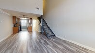 Located on Lawler Street in the Palms neighborhood of Los Angeles, this two-story residence offers a thoughtfully designed layout with a blend of modern finishes and distinctive architectural details. The main living area makes an immediate impression with its soaring double-height ceilings, which amplify the sense of space and allow natural light to flow freely throughout. A stone-clad fireplace serves as a focal point in the living room, complemented by wide-plank wood-style flooring that extends across the main level. A striking metal staircase connects the two floors, adding an industrial design element to the interior.

The kitchen is well-equipped with rich wood cabinetry, granite countertops, stainless steel appliances including a gas range and refrigerator, and a mosaic tile backsplash. A ceiling fan and natural light from a window brighten the space.

Upstairs, the bedrooms feature exposed dark wood beam ceilings that lend a rustic character to the rooms. Soft carpeting and louvered shuttered windows provide comfort and privacy. The bathrooms are finished with warm wood vanities, granite countertops, large mirrors, and brushed nickel fixtures, maintaining a consistent, polished aesthetic throughout the home.