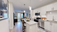 This thoughtfully designed one-bedroom, one-bathroom residence offers a cohesive open-concept layout that maximizes every square foot. The kitchen is a standout feature, showcasing crisp white cabinetry, granite countertops, a full suite of stainless steel appliances including a refrigerator with ice maker, electric range, microwave, and dishwasher, as well as a central island with seating for two — ideal for casual dining or entertaining. Pendant lighting above the island adds a refined touch. Light wood-style flooring flows seamlessly throughout the entire residence, enhancing the sense of continuity and space. The living room is bright and welcoming, benefiting from natural light through a glass door and large windows dressed with roman shades and navy drape accents. A ceiling fan adds comfort to the space. The bedroom is a calm retreat, featuring a ceiling fan, a generously sized window for natural light, a dedicated closet, and room for a full furniture arrangement. The bathroom is finished with granite-topped white vanity cabinetry, a large mirror, and wood-style flooring consistent with the rest of the residence. Neutral wall tones throughout create a clean, modern aesthetic that is both functional and inviting.