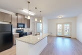 Located at 430 Mosby Blvd in Berryville, VA, this well-appointed one-bedroom, one-bathroom residence offers a thoughtfully designed single-floor layout. The open-concept living area seamlessly connects the kitchen, dining, and living spaces, creating an efficient and welcoming environment. The kitchen is a standout feature, boasting granite countertops on a central island with an integrated sink, pendant lighting, medium-toned cabinetry reaching to the ceiling, and black appliances including a refrigerator, range, and over-the-range microwave. Wood-style flooring runs throughout the main living areas, adding warmth and continuity. A glass-paned door leads to a private patio, allowing natural light to fill the living space. The bedroom features plush carpeting, a generous window with outdoor views of surrounding greenery, and access to a dedicated closet. The bathroom is equipped with light wood-style flooring, a dark-cabinetry vanity with a wide mirror, and accessibility-friendly grab bars. Additional conveniences include a dedicated laundry area and pantry. The unit's clean white walls and neutral palette create a bright, move-in-ready atmosphere throughout.