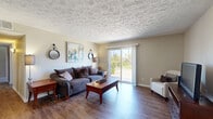 This thoughtfully designed single-floor residence offers two bedrooms and two bathrooms within a comfortable and functional layout. The living room serves as the heart of the home, featuring warm hardwood-style flooring, a textured ceiling, and a sliding glass door that floods the space with natural light and provides views of the surrounding greenery — a standout feature of this home. The adjacent dining area continues the hardwood flooring and includes a ceiling fan with light fixture, adding both style and practicality to the space. The kitchen is equipped with light wood cabinetry and granite-toned countertops, offering ample workspace and storage. Both bedrooms are carpeted and well-lit with windows overlooking the natural outdoor surroundings. The generously sized primary bedroom benefits from its own dedicated closet — a walk-in space with dual wire shelving systems and plush carpet underfoot. The two bathrooms feature wood-toned vanity cabinetry, granite-style countertops, large mirrors, and tub-shower combinations with hardwood-style flooring. Neutral warm tones carry throughout the home, creating a cohesive and inviting ambiance from room to room.