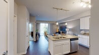 Located at 200 Hudson Court in Wheeling, Illinois, this well-appointed 2-bedroom, 1-bathroom residence offers a thoughtfully designed single-level layout ideal for comfortable everyday living. The open-concept kitchen and living area forms the heart of the home, where the kitchen impresses with crisp white shaker cabinetry, granite countertops, stainless steel appliances including a gas range, microwave, and refrigerator, and a peninsula island with bar seating — all illuminated by stylish pendant and track lighting overhead. Dark hardwood flooring runs throughout the main living areas, adding warmth and contrast to the neutral palette. The living room is bright and inviting, benefiting from large sliding glass doors that flood the space with natural light and provide access to an outdoor area with pleasant greenery views. A carpeted hallway connects to the two bedrooms, each offering soft carpet underfoot and windows that bring in natural light. The primary bedroom is generously sized, providing ample room for a full furniture arrangement. A dedicated closet adds practical storage. The full bathroom features a tub-shower combination with classic subway tile, a granite-topped vanity, and tile flooring. The entrance foyer completes the layout, offering a clean and welcoming transition into the home.