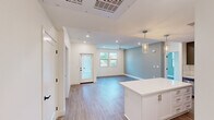 This thoughtfully designed single-story home offers three bedrooms and three full bathrooms within a well-organized, open-concept floor plan. Light-toned wood-look flooring runs seamlessly throughout, creating a cohesive and contemporary feel across every room.

The kitchen is a standout feature, boasting gray shaker-style cabinetry, a white quartz countertop island with pendant lighting, a classic white tile backsplash, and a full suite of stainless steel appliances including a gas range, microwave, dishwasher, and refrigerator. The kitchen opens directly into the living area, which is fitted with recessed lighting, a ceiling fan, and a glass-paneled entry door that invites natural light into the space. Multiple windows frame outdoor greenery, enhancing the bright and airy ambiance.

The primary bedroom is a comfortable retreat with a ceiling fan, direct access to its own en-suite bathroom, and a view into the kitchen area. The bathrooms are finished in a clean, modern style with white cabinetry, quartz countertops, framed mirrors, and wood-look flooring. One bathroom features accessibility-friendly grab bars. The secondary bedrooms are well-lit with large windows offering pleasant outdoor views. Clean white walls and crisp trim work throughout give the home a fresh, move-in-ready appearance.