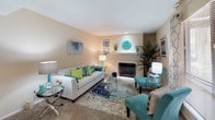 This single-story residence is thoughtfully laid out across a comfortable footprint, offering a cohesive blend of functional spaces finished in warm neutral tones. The living room serves as the heart of the home, featuring plush carpeting, a fireplace with a decorative mantel, and large windows dressed with patterned curtains that allow natural light to fill the room. Recessed lighting complements the natural light, creating a welcoming ambiance.

The kitchen is efficiently designed with white cabinetry, a coil-burner electric range, and speckled granite-style countertops. A pass-through opening connects the kitchen directly to the living area, enhancing the open feel between the two spaces.

The bedroom is generously proportioned, featuring soft carpeting, a window with blinds and decorative curtains, and ample wall space. A textured ceiling adds subtle character throughout the unit.

The bathroom includes a tub-shower combination with tiled surround, a white vanity with storage, dark hardwood-style flooring, and a framed mirror. Neutral wall tones are consistent throughout, tying each room together with a clean, cohesive aesthetic.