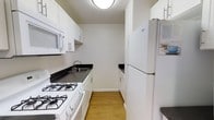 Unit 2009 is a 2-bedroom, 2-bathroom residence thoughtfully designed across a single floor. The galley-style kitchen is a standout feature, outfitted with white cabinetry, dark countertops, and a full suite of white appliances including a gas range, over-the-range microwave, and a full-size refrigerator. The light wood-tone flooring adds warmth to the clean, bright aesthetic, while the crisp white walls and flush ceiling lighting keep the space feeling open and airy. The efficient layout of the kitchen maximizes storage and counter space, with cabinetry lining both sides to provide ample organization. The two bedrooms offer comfortable private retreats, complemented by two full bathrooms for added convenience. The overall design of the unit emphasizes clean lines and a neutral palette, creating a versatile backdrop that suits a variety of interior styles. This residence presents a practical and well-appointed living environment ideal for those seeking a functional yet inviting home.
