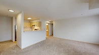 This single-floor residence offers a clean, functional layout with a thoughtful blend of comfort and practicality. The open-concept living area is generously proportioned, finished with plush wall-to-wall carpeting and neutral-toned walls that create a bright, welcoming ambiance. A half-wall pass-through seamlessly connects the living space to the kitchen, which features light maple cabinetry, white countertops, a stainless steel refrigerator, an electric range, and hardwood-style flooring that adds warmth to the space.

The residence includes multiple bedrooms, each carpeted and filled with natural light from large windows fitted with blinds. One bedroom benefits from a baseboard heater, while another enjoys direct access to a private balcony through sliding glass doors, extending the living space outdoors. The bedrooms offer clean, versatile spaces adaptable to a variety of needs.

The bathroom is efficiently designed with a single vanity topped with a white countertop, a tub-shower combination, and hardwood-style flooring that complements the kitchen. A central hallway connects the rooms, providing a logical and practical flow throughout the unit. Overall, the space presents a neutral, move-in-ready environment with consistent finishes and ample natural light throughout.