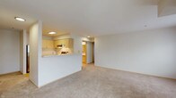 This single-floor residence offers a clean, functional layout with a thoughtful blend of comfort and practicality. The open-concept living area is generously proportioned, finished with plush wall-to-wall carpeting and neutral-toned walls that create a bright, welcoming ambiance. A half-wall pass-through seamlessly connects the living space to the kitchen, which features light maple cabinetry, white countertops, a stainless steel refrigerator, an electric range, and hardwood-style flooring that adds warmth to the space.

The residence includes multiple bedrooms, each carpeted and filled with natural light from large windows fitted with blinds. One bedroom benefits from a baseboard heater, while another enjoys direct access to a private balcony through sliding glass doors, extending the living space outdoors. The bedrooms offer clean, versatile spaces adaptable to a variety of needs.

The bathroom is efficiently designed with a single vanity topped with a white countertop, a tub-shower combination, and hardwood-style flooring that complements the kitchen. A central hallway connects the rooms, providing a logical and practical flow throughout the unit. Overall, the space presents a neutral, move-in-ready environment with consistent finishes and ample natural light throughout.