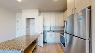 Located on Cross Street in Lanham, MD, this well-appointed one-bedroom, one-bathroom residence offers a thoughtfully designed single-floor layout. The open-concept living and kitchen area creates a bright, airy atmosphere, anchored by light wood-look flooring and neutral tones throughout. The kitchen is a standout feature, boasting white shaker-style cabinetry extending to the ceiling for ample storage, granite countertops, a central island with matching granite surface, and a full suite of stainless steel appliances including a refrigerator, electric range, built-in microwave, and dishwasher. The living area flows naturally from the kitchen and opens to a private balcony through sliding glass doors fitted with vertical blinds, allowing generous natural light. The bedroom is comfortably sized, finished with plush carpet and a large window overlooking the exterior, bringing in additional natural light. A dedicated closet provides convenient storage. The bathroom features a soaking tub with tiled surround, a granite-topped vanity with modern cabinetry, a backlit mirror, and wood-look flooring, completing a clean and contemporary aesthetic throughout the unit.