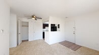 Located at 919 Lewis Creek Ln in Shelbyville, Indiana, this one-bedroom, one-bathroom residence offers a well-organized single-floor layout designed for efficient, comfortable living. The open-concept living area features neutral-toned carpet, bright white walls, and a ceiling fan with integrated lighting, creating a clean and airy atmosphere. Natural light filters in through slatted blinds, enhancing the sense of space. The kitchen is thoughtfully appointed with dark espresso cabinetry, granite-style countertops, and black appliances including a refrigerator, electric range, and over-the-range microwave. Wood-look vinyl flooring in the kitchen adds a practical yet stylish touch, and a pass-through opening connects the kitchen visually to the living area. The bedroom is a comfortable, carpeted retreat with a dedicated closet featuring louvered doors, providing ample storage. An additional closet is accessible from the main living area, adding further storage convenience. The bathroom is well-equipped with dark vanity cabinetry, a granite-look countertop with an undermount sink, and a full tub-shower combination with white tile surround and a curved curtain rod. Wood-look flooring completes the bathroom's clean, cohesive aesthetic throughout this tidy and functional home.