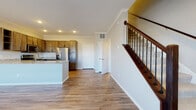 This two-story residence is thoughtfully designed with a clean, contemporary aesthetic throughout. The main floor features an open-concept layout where the living area flows seamlessly into the kitchen. Wood-look plank flooring extends across the entire main level, complemented by crown molding and recessed lighting. A staircase with a warm wood railing and dark iron balusters serves as a functional architectural accent, leading to the upper floor.

The kitchen is well-equipped with medium-toned shaker-style cabinetry, granite countertops, a peninsula island, and a full suite of stainless steel appliances including a refrigerator with ice maker, electric range, and over-the-range microwave. A main-floor half bath features a classic pedestal sink and mirror.

Upstairs, the carpeted bedrooms offer a comfortable retreat, with multiple windows providing natural light and outdoor views. A full bathroom on this level includes a tub-shower combination, granite vanity countertop, wood cabinetry, and hardwood-style flooring. A spacious walk-in closet with wrap-around wire shelving and carpeted flooring provides generous storage. The overall ambiance is neutral, modern, and move-in ready.