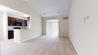 This single-floor residence offers a thoughtfully designed layout that balances comfort and functionality. The living area is immediately welcoming, showcasing vaulted ceilings that lend a sense of openness and volume to the space. Neutral-toned carpet flows throughout, complementing the warm beige walls. A fireplace with a tiled surround and a built-in mantle serves as a focal point in the living room, while sliding glass doors fitted with vertical blinds open to an outdoor area, flooding the room with natural light. An elegant chandelier illuminates the adjacent dining area, which connects seamlessly to the kitchen via a granite-topped breakfast bar.

The kitchen is well-equipped, featuring rich dark-stained cabinetry, granite countertops, black appliances including a range, microwave, refrigerator, and dishwasher, all set atop clean white tile flooring. A window above the sink area allows natural light to brighten the workspace.

The bedrooms are carpeted and serene, each offering generous closet space. One bedroom features a large window with views of the surrounding neighborhood. The bathroom includes a full tub and shower combo with classic white subway tile surround and chrome fixtures, finished with tile flooring for easy maintenance. Overall, the space presents a clean, neutral palette throughout.