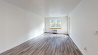 Located at 1323 SW Cherry Park Rd in Troutdale, Oregon, this well-appointed one-bedroom, one-bathroom unit offers a thoughtfully designed single-floor layout. The open-concept living, dining, and kitchen area forms the heart of the unit, featuring durable wood-look flooring throughout and crisp white walls that maximize brightness. A large window in the living area frames views of mature greenery outside, while a wall-mounted HVAC unit ensures year-round comfort. The kitchen is efficiently designed with light maple cabinetry, white countertops, and a full suite of stainless steel appliances including a refrigerator, electric range, and dishwasher. A dedicated entry area provides a practical transition space upon arrival. The bedroom offers a comfortable footprint with recessed lighting and direct access to a walk-in closet equipped with wire shelving for organized storage. The hallway connects all areas seamlessly, leading to the full bathroom, which features a glass-enclosed shower and a clean, functional layout. A private patio extends the living space outdoors. Wood-look flooring flows consistently throughout the unit, contributing to a cohesive and modern aesthetic.