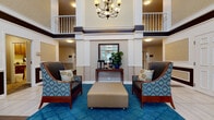 Located at 1015 Sibley Memorial Hwy in Saint Paul, this residential community offers a refined and comfortable living environment across its thoughtfully designed common spaces. The grand entrance lobby immediately impresses with its soaring two-story atrium, anchored by an elegant chandelier and framed by upper-level balconies with white railings. Rich blue carpeting, patterned accent chairs, and a console table with lush greenery create a warm and welcoming first impression.

Wide, well-lit corridors with patterned carpeting connect residents to key amenities, including a dedicated Club Room. This expansive gathering space features a coffered ceiling, large windows that flood the room with natural light, and sweeping outdoor views. Comfortable leather seating, patterned armchairs, a wall-mounted television, and multiple dining tables make it an ideal space for both relaxation and socializing.

A fully equipped kitchen with rich hardwood floors, dark cabinetry, stainless steel appliances, granite countertops, and a center island with bar seating adds a functional and elegant touch. Throughout the community, warm wall sconces, neutral tones, and classic furnishings contribute to a consistently inviting and upscale ambiance suited for everyday living.