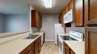 This two-story home is designed with a practical and comfortable layout across both levels. The galley-style kitchen is efficiently arranged with warm medium-toned wood cabinetry lining both walls, offering generous upper and lower storage. Light-toned countertops provide ample prep space, and white appliances — including an electric range, over-the-range microwave, refrigerator, and dishwasher — are included. Stone-look tile flooring runs through the kitchen and extends into the connecting hallway, which features soft gray walls and clean white trim, guiding residents through the home's interior.

The bedrooms are carpeted in neutral tones and each include ceiling fans with integrated lighting. Natural light enters through blinds-fitted windows, and one room features a vaulted ceiling with a built-in desk ledge, adding a functional touch. The bathrooms are finished with stone-look tile flooring, wood vanities with light countertops, and full tub-shower combinations. One bathroom includes a more spacious layout with a separate water closet. Throughout the home, a consistent gray-toned color palette and white trim create a clean, cohesive aesthetic.
