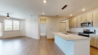 This well-appointed 2-bedroom, 2-bathroom residence is thoughtfully designed on a single floor, offering a functional and modern layout. The open-concept kitchen and living area serves as the heart of the home, featuring a central island with a granite countertop and undermount sink, light wood cabinetry, a subway tile backsplash, and a full suite of stainless steel appliances including a range, microwave, and French door refrigerator. Warm wood-look plank flooring flows seamlessly throughout the main living areas, complementing the neutral, light-toned walls.

The living room is bright and inviting, with a ceiling fan, a glass door that opens to a private balcony, and windows that invite natural light and outdoor views. A pendant-lit dining area connects the kitchen to the rest of the living space.

Both bedrooms are carpeted and generously sized, with the primary bedroom offering walk-in closet access and a ceiling fan with natural light from multiple windows. Each bathroom is finished with large-format tile flooring, wood-tone vanity cabinetry, and granite countertops. The secondary bathroom features a tiled tub-shower combination, while the primary bath offers a dedicated vanity with a well-lit mirror. Two hallways connect the private areas efficiently, completing this clean and contemporary layout.