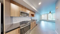 Located at 104 12th Ave in Seattle's Capitol Hill neighborhood, this modern studio unit offers a thoughtfully designed open-concept layout that maximizes every square foot. Polished concrete floors run throughout the entire space, lending an industrial-chic aesthetic that ties the rooms together cohesively.

The kitchen is outfitted with warm wood cabinetry, granite-style countertops, a white subway tile backsplash, and a full suite of stainless steel appliances including an electric range, microwave, and dishwasher. The kitchen flows seamlessly into the open living area, which features large windows that fill the room with natural light and offer views of the surrounding cityscape. A sleek ceiling fan with an integrated light fixture adds both style and function overhead. An exposed concrete accent panel on one wall provides an architectural focal point, reinforcing the unit's modern urban character.

The combined bathroom and laundry room is efficiently arranged, featuring a stacked washer and dryer, a wood-accented vanity, and clean white walls that keep the space feeling bright and orderly. A dedicated closet provides practical storage. This unit delivers a clean, contemporary living experience in one of Seattle's most vibrant neighborhoods.