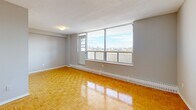 Located on the 9th floor at 3400 Weston Rd in Toronto's Humber Summit neighbourhood, this one-bedroom, one-bathroom unit offers a practical and well-organized layout across a single floor. Warm parquet flooring runs throughout the main living areas, adding a classic character to the space. The living room is generously proportioned for its scale, featuring large floor-to-ceiling windows that flood the room with natural light and frame expansive elevated views of the Toronto skyline — a true highlight of the unit. The bedroom is a comfortable size, also benefiting from a large window with city views and baseboard heating. The kitchen is efficiently laid out with white cabinetry, granite-style countertops, tile flooring, and white appliances including a refrigerator and electric range, offering all the essentials in a clean, functional arrangement. The bathroom features distinctive green mosaic tile flooring, beige wall tiling in the tub-shower surround, a toilet, and a vanity with a stone-topped countertop, all complemented by a small window for natural ventilation. Throughout the unit, neutral grey walls and consistent parquet flooring create a cohesive and understated aesthetic.