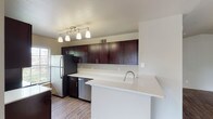 This 2-bedroom, 2-bathroom apartment offers a well-designed single-floor layout with a thoughtful blend of style and functionality. The kitchen is a standout feature, equipped with rich dark-cabinetry, light quartz countertops, stainless steel appliances including a refrigerator and dishwasher, and a peninsula that opens toward the living area — ideal for both cooking and entertaining. Wood-style flooring runs throughout the main living spaces, adding warmth and continuity.

The open living area benefits from natural light and features vaulted ceilings, with sliding glass doors leading to a private balcony that overlooks greenery. Both bedrooms are generously sized, carpeted for comfort, and include ceiling fans. The primary bathroom is appointed with a dual-sink vanity featuring dark cabinetry and light countertops, a walk-in closet, and a separate shower. The second bathroom includes a tiled shower-tub combination and matching finishes consistent with the rest of the unit.

Overall, the space presents a clean, neutral palette throughout, making it highly adaptable to a variety of interior styles while offering practical, comfortable living.