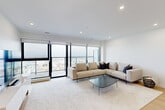 Located at 6070 Almon Street in Halifax, NS, this thoughtfully designed 3-bedroom, 2-bathroom residence offers a bright, contemporary living experience with a clean, minimalist aesthetic throughout. Light hardwood flooring and recessed lighting flow seamlessly from the entry hallway into the open-concept living and kitchen area, creating a cohesive and airy atmosphere. The living room is anchored by floor-to-ceiling windows and sliding glass doors that open onto a private balcony, offering striking panoramic views of the city and waterfront. The kitchen is a standout feature, showcasing sleek white cabinetry extending to the ceiling, stainless steel appliances, and a large waterfall-edge island with bar seating — ideal for both everyday living and entertaining. A dedicated dining area with hardwood flooring complements the open layout. The generously sized primary bedroom benefits from large windows framing expansive views, while all bedrooms feature the same warm hardwood floors and crisp white walls. Both bathrooms are finished with large-format neutral tiles, including a full soaker tub and shower combination. A dedicated office and in-unit closet add functional versatility to this well-appointed residence.