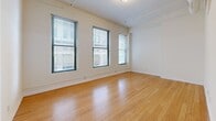 Located at 2013 Ontario Street in Cleveland, Ohio, this two-bedroom, two-bathroom residence offers a well-designed single-floor layout with consistent hardwood flooring flowing throughout. The primary living area is generously proportioned, featuring multiple tall windows that allow abundant natural light to fill the space and offer views of the surrounding urban streetscape.

The kitchen is a standout feature, showcasing rich cherry wood cabinetry extending to the ceiling, granite countertops, a central island with matching granite surface, stainless steel appliances including a refrigerator, electric range, microwave, and dishwasher, and pendant lighting overhead — all combining to create a functional and visually appealing cooking space.

Both bedrooms feature the same warm hardwood flooring and double-door closets. The primary bedroom is spacious with large windows, while the second bedroom includes elevated horizontal windows that provide natural light while maintaining privacy. Each room is finished with clean white walls and crisp trim throughout.

Both bathrooms are identically appointed with light tile flooring, full tub/shower combinations featuring large-format wall tile and a decorative mosaic accent border, and cherry wood vanities with granite countertops. A connecting hallway ties all rooms together in a clean, cohesive layout.