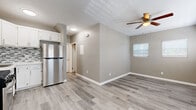 Located at 1032 S Normandie Ave in Los Angeles, this 2-bedroom, 2-bathroom single-story unit offers a efficiently designed layout with contemporary finishes throughout. Light gray wood-style vinyl flooring runs continuously across all rooms, creating a cohesive and easy-to-maintain interior.

The combined kitchen and living area serves as the heart of the unit. The kitchen is well-appointed with white cabinetry, white quartz countertops, a gray-and-white mosaic tile backsplash, and a full suite of stainless steel appliances including a gas range, microwave, and refrigerator. A wall-mounted HVAC unit provides climate control, and a window near the entry allows natural light into the space.

The living area is bright and open, featuring multiple windows with white blinds and a ceiling fan overhead. Both bedrooms continue the light flooring and neutral gray wall tones. The primary bedroom includes a ceiling fan, while the second bedroom features mirrored sliding closet doors. Each room benefits from natural light through well-placed windows.

The two bathrooms are finished with marble-style tile. One features a tub-shower combo with sliding glass doors, while the second offers a stand-alone glass-enclosed shower with a white vanity.