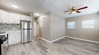 Located at 1032 S Normandie Ave in Los Angeles, this 2-bedroom, 2-bathroom single-story unit offers a efficiently designed layout with contemporary finishes throughout. Light gray wood-style vinyl flooring runs continuously across all rooms, creating a cohesive and easy-to-maintain interior.

The combined kitchen and living area serves as the heart of the unit. The kitchen is well-appointed with white cabinetry, white quartz countertops, a gray-and-white mosaic tile backsplash, and a full suite of stainless steel appliances including a gas range, microwave, and refrigerator. A wall-mounted HVAC unit provides climate control, and a window near the entry allows natural light into the space.

The living area is bright and open, featuring multiple windows with white blinds and a ceiling fan overhead. Both bedrooms continue the light flooring and neutral gray wall tones. The primary bedroom includes a ceiling fan, while the second bedroom features mirrored sliding closet doors. Each room benefits from natural light through well-placed windows.

The two bathrooms are finished with marble-style tile. One features a tub-shower combo with sliding glass doors, while the second offers a stand-alone glass-enclosed shower with a white vanity.